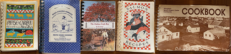 A row of old, well-worn, beloved, Native American cookbooks.