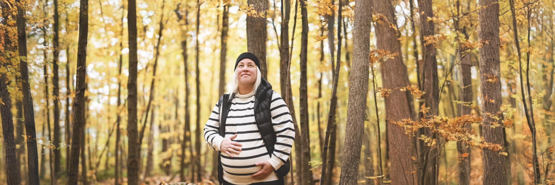 Young pregnant woman walking through a forest in autumn.