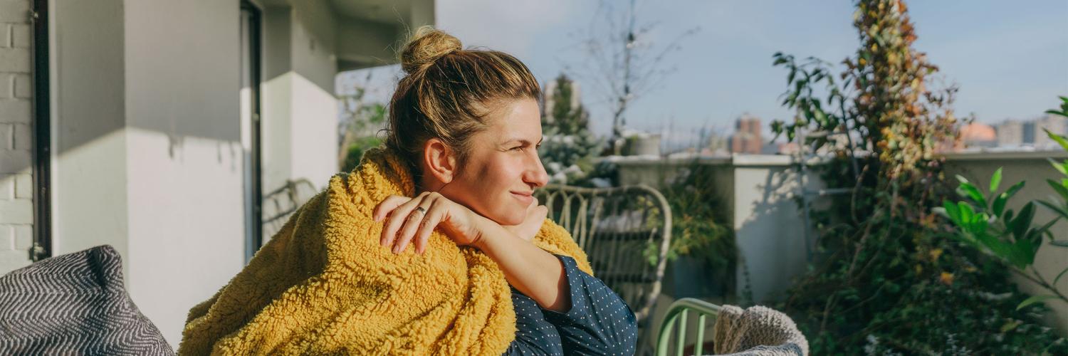 Woman sitting on a balcony looking out a the view.