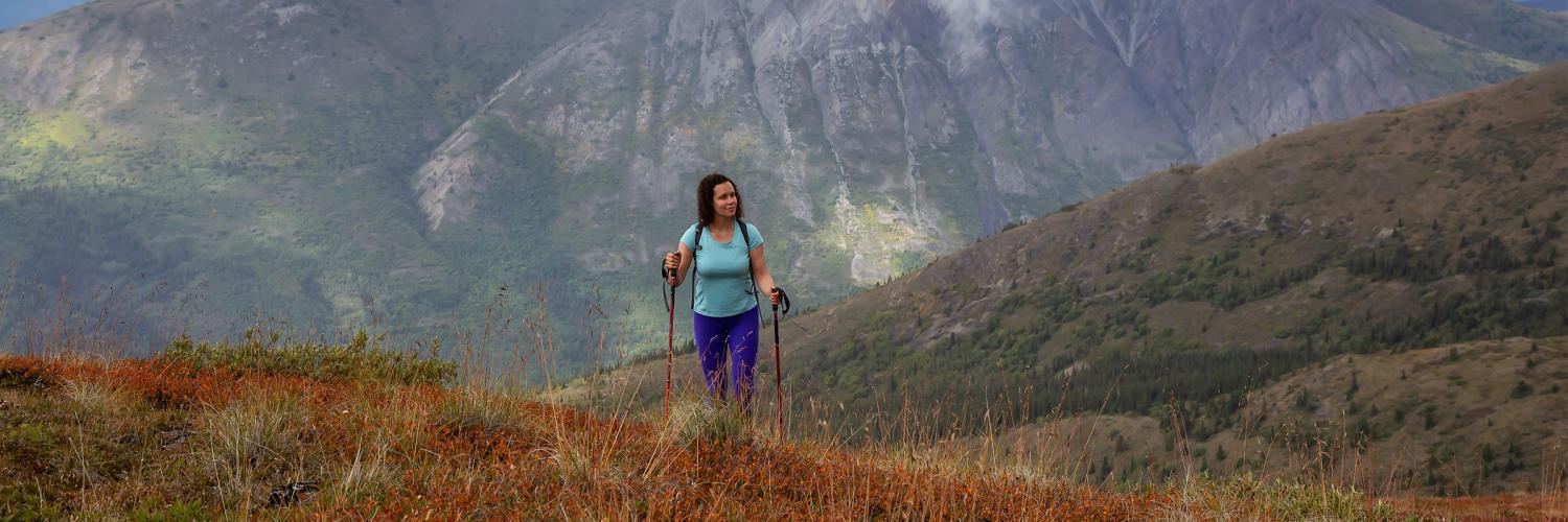 Woman hiking in the mountains using two walking poles.