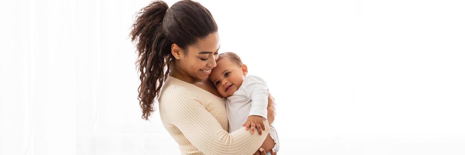 HE Spotlight: Doula benefit Young woman lying on a bed facing her infant.