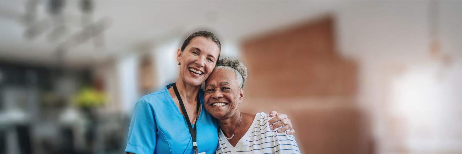 A photo of a smiling female health provider hugging her client located in an office.