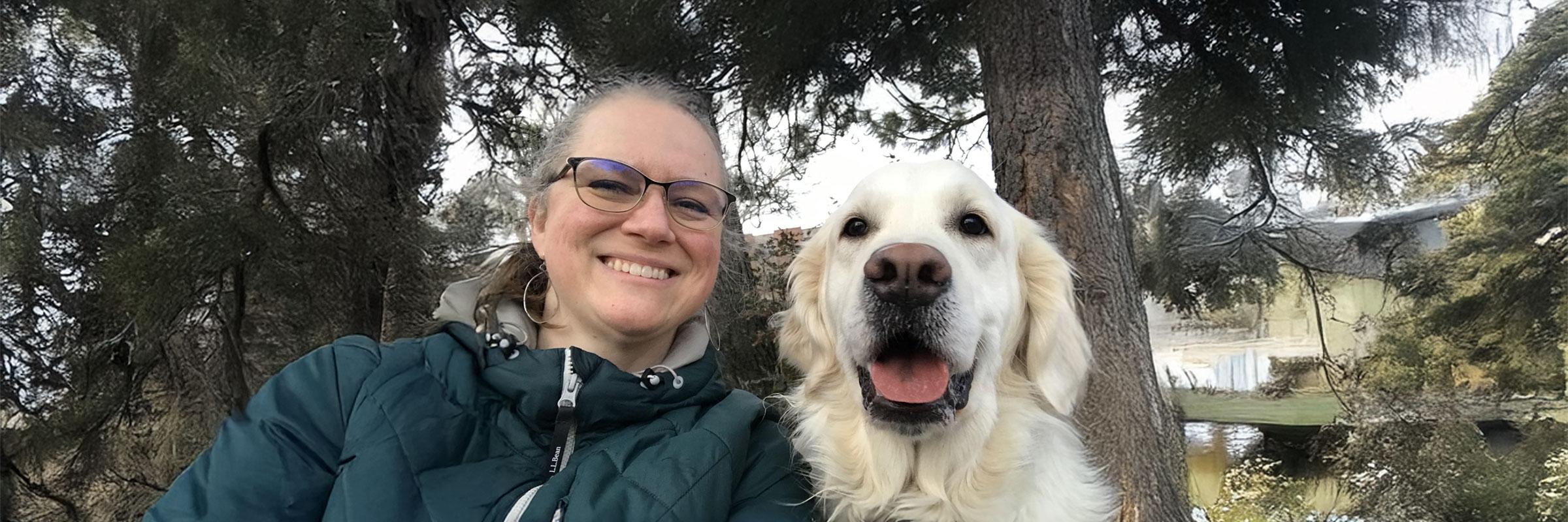 V. Wiss and her golden retriever surrounded by trees.