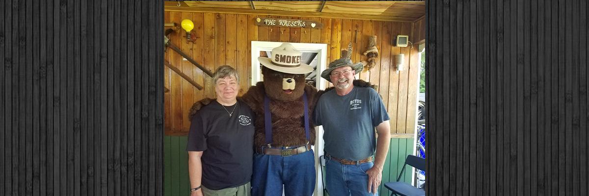 Randy Jones and wife posing for photo with Smokey Bear