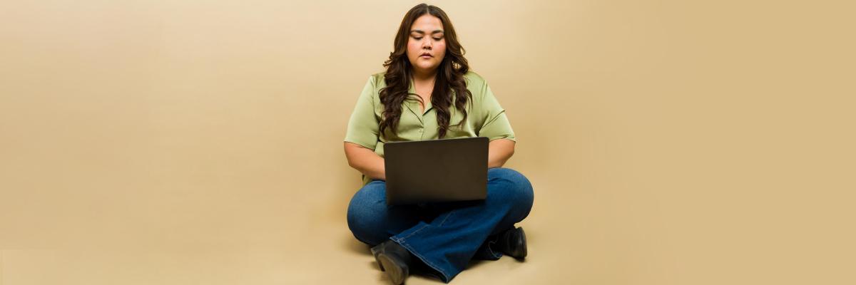 A woman sitting cross-legged uses a laptop