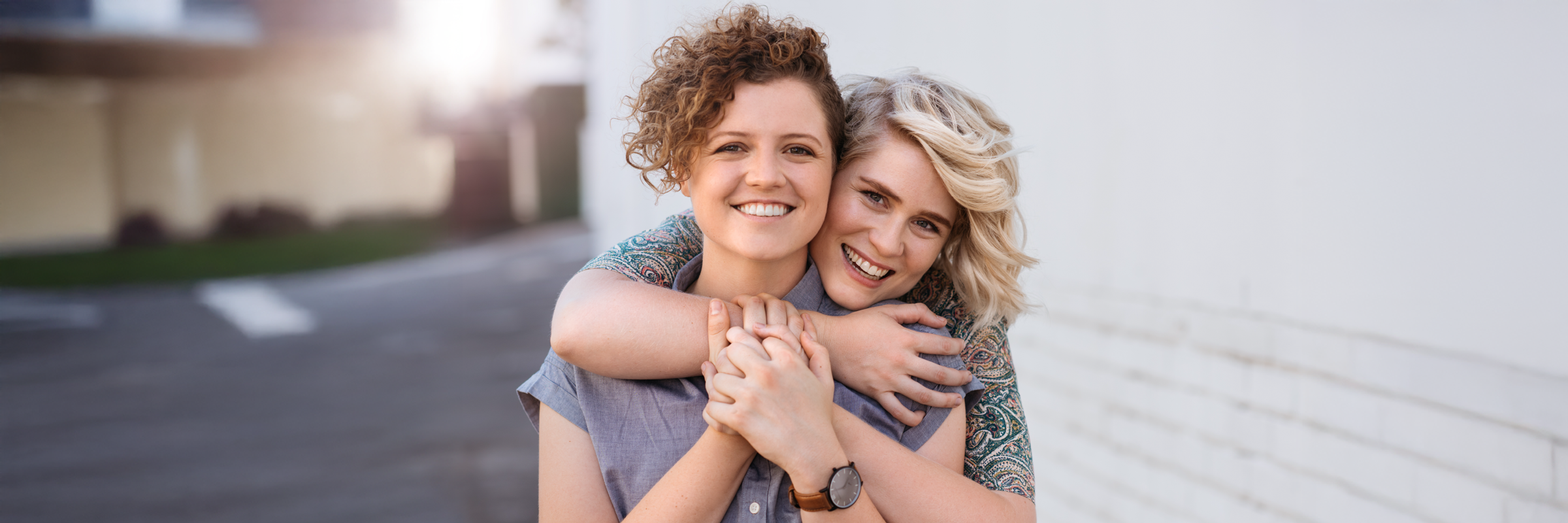 A photo of two female individuals hugging and smiling. 