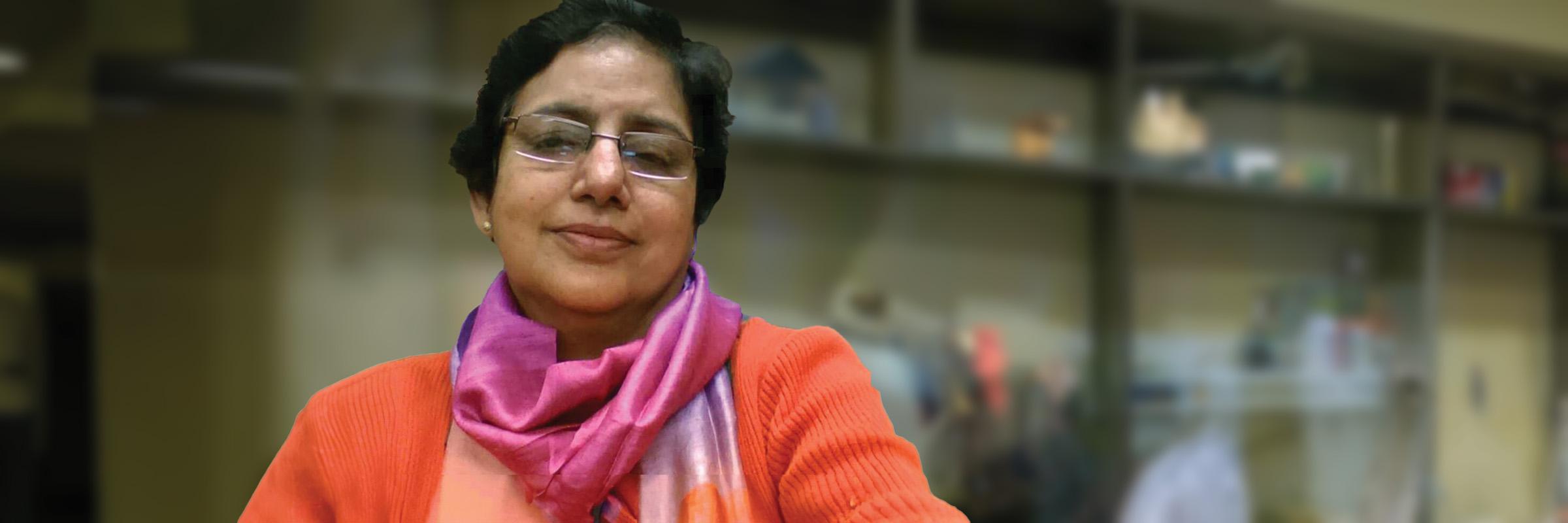 Photo of a female client smiling with a blurred background of shelf behind her.