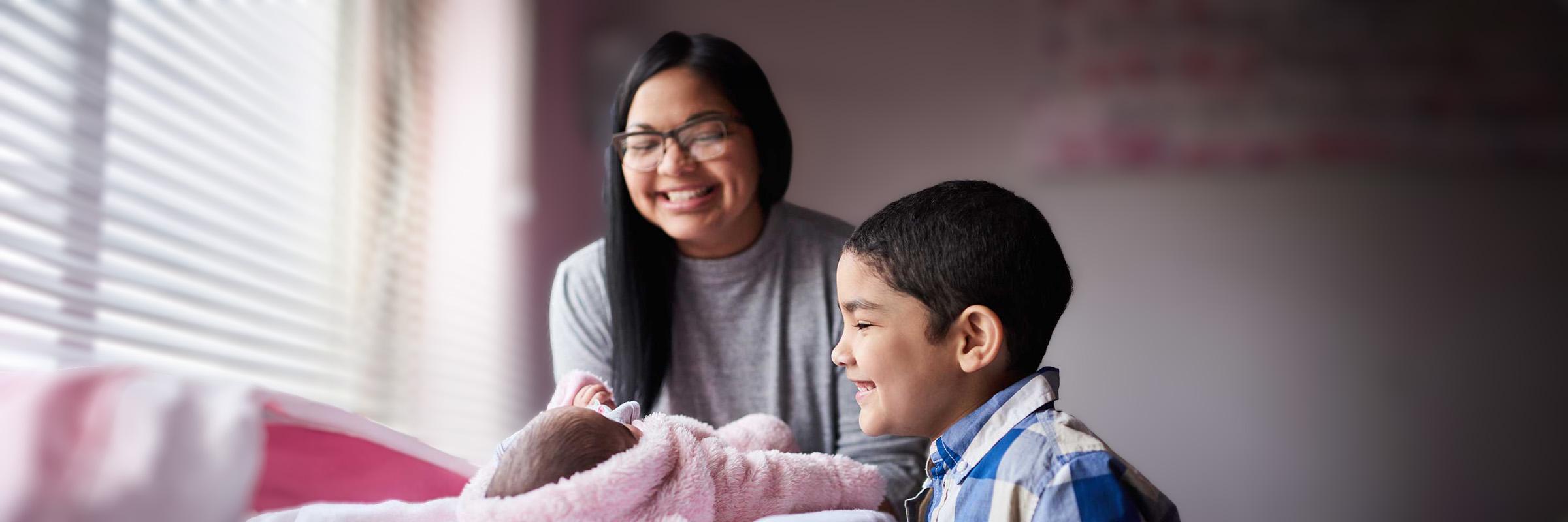 Photo of a mother and her two children, one a newborn and the other a toddler. 