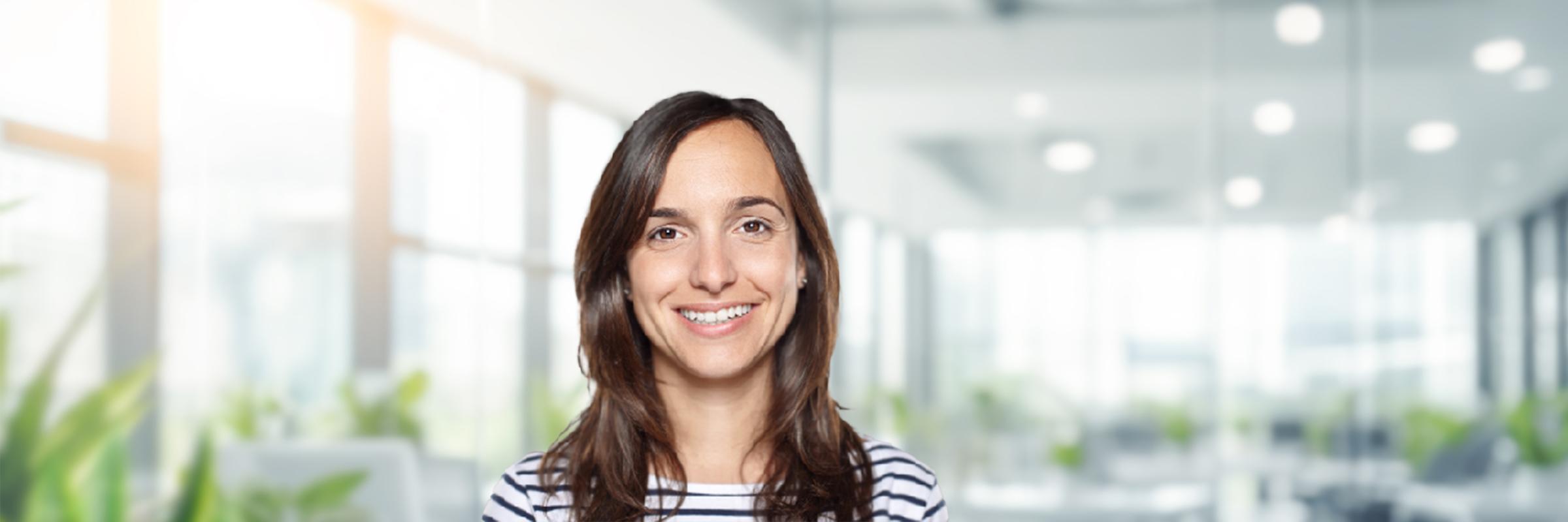 Libby Watson standing in a bright office, smiling, facing the camera.