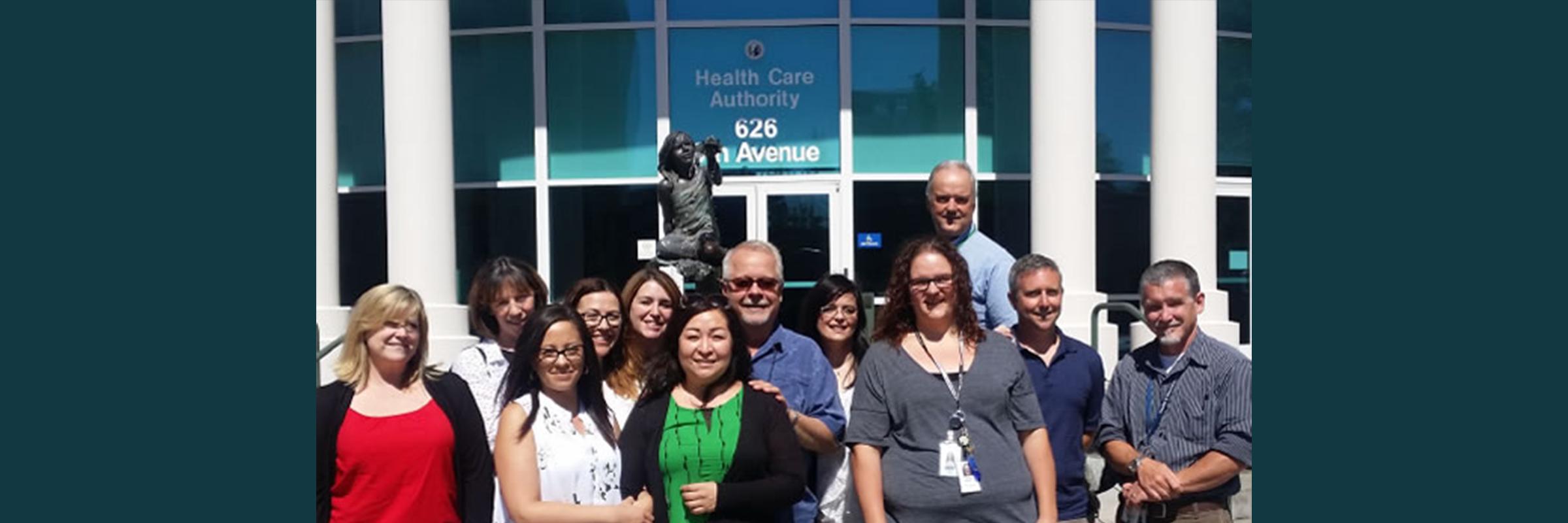 The OMEP team standing together in front of the fountain outside the Health Care Authority offices at Cherry Street Plaza.